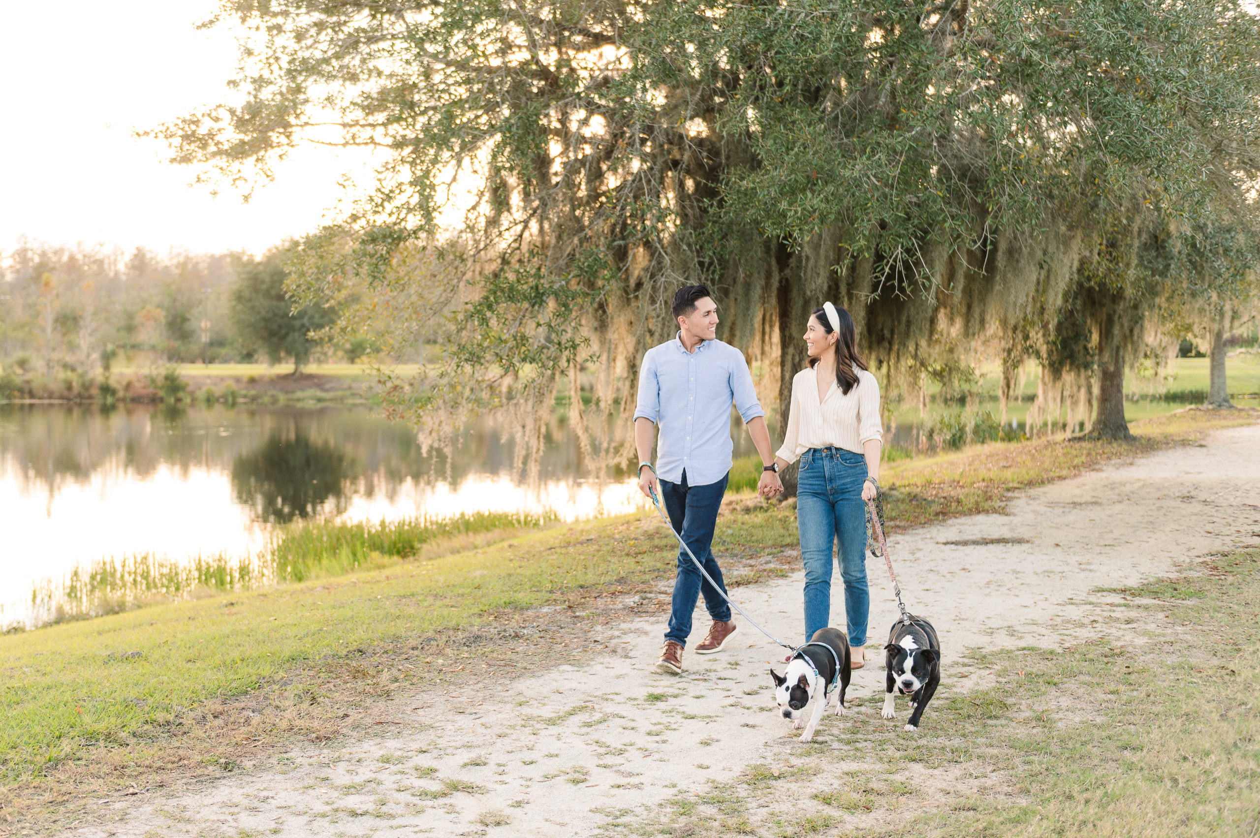 Couple walking their 2 boston terriers in Florida by a pond