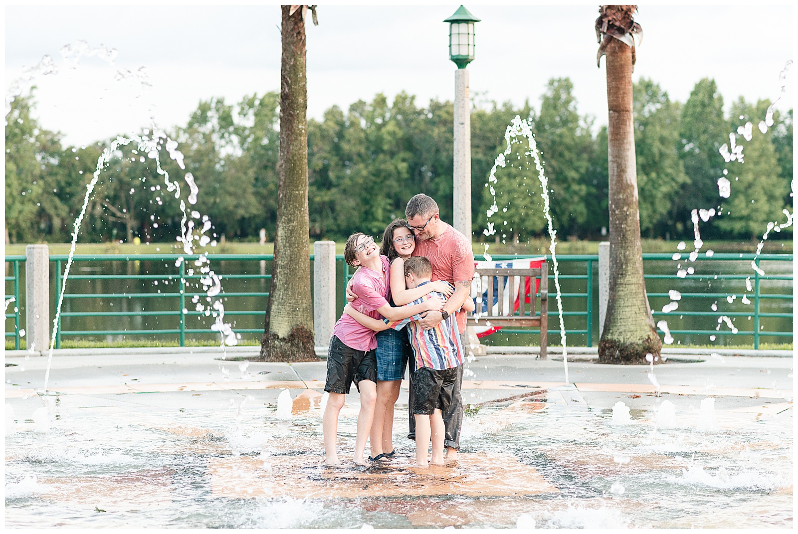 Father and three children having fun playing in a fountain during a family photo session