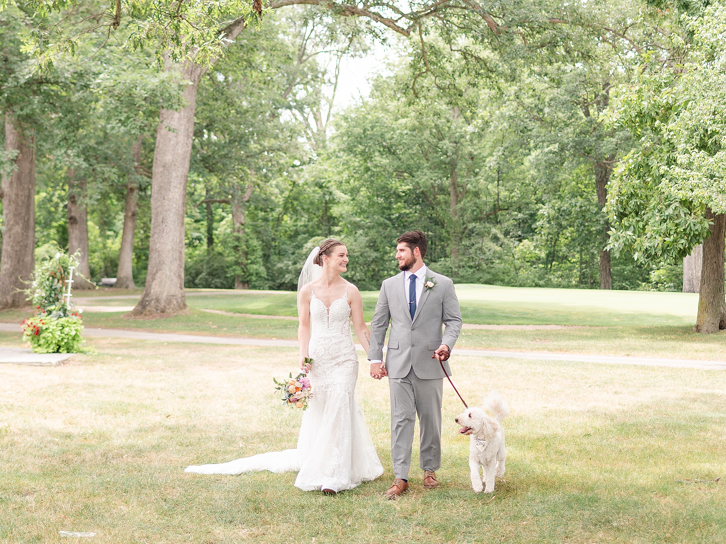 Bride and groom walking their white dog on a golf course in Anderson, Indiana