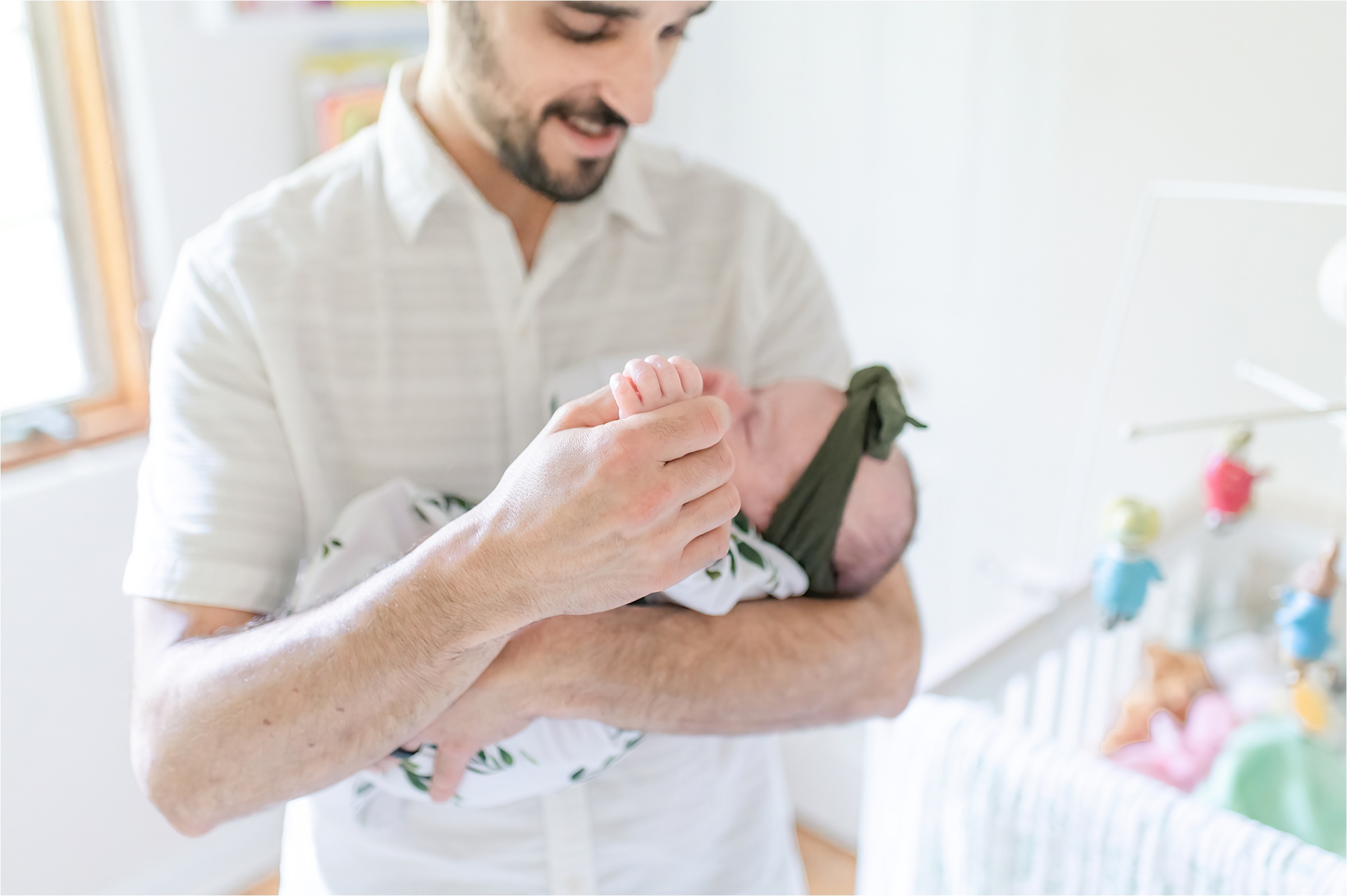 Dad holding baby in nursery | Lifestyle Newborn Photography