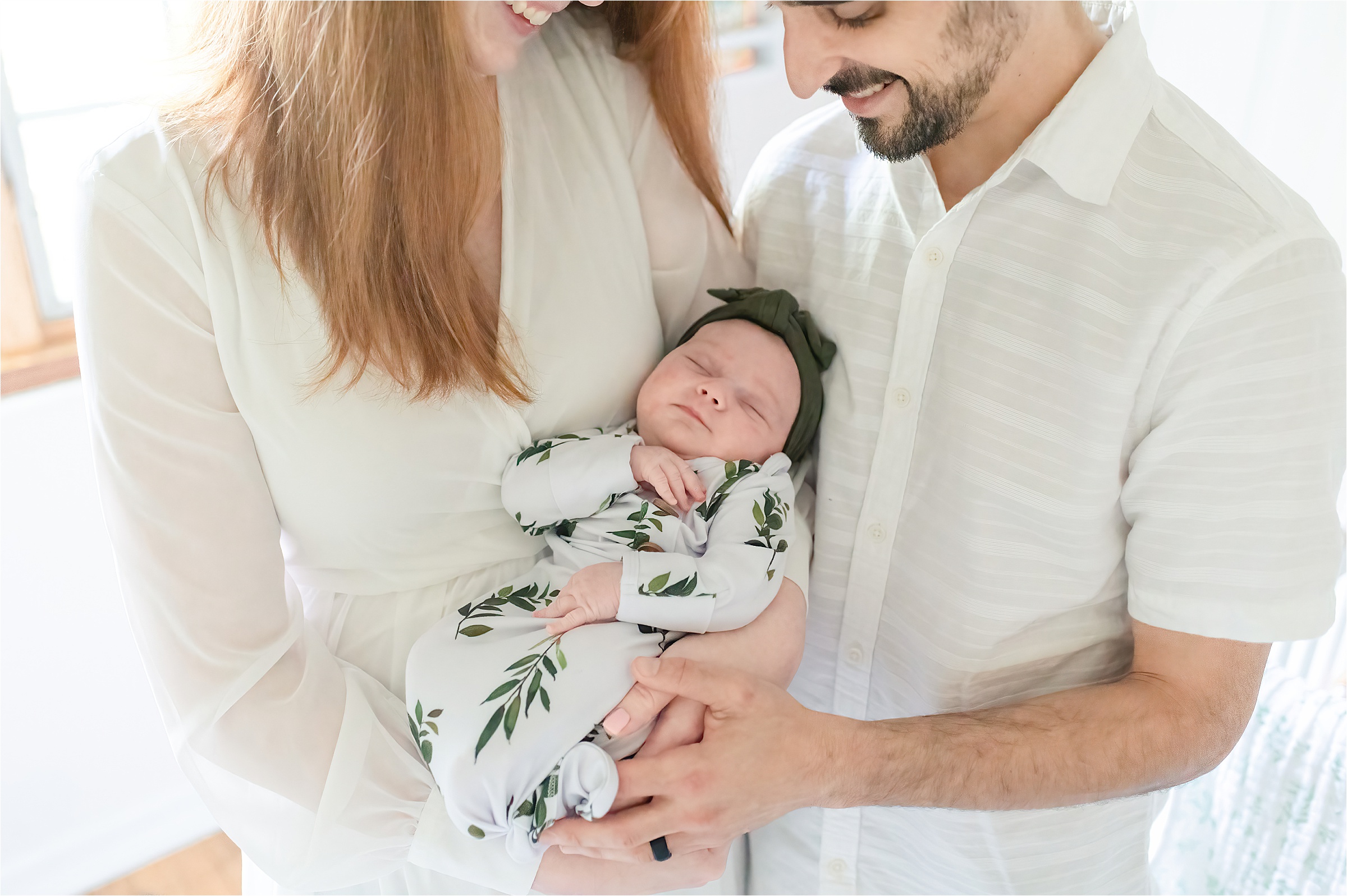 Parents holding baby girl wrapped ina 
 floral green swaddle | Lifestyle Newborn Photography