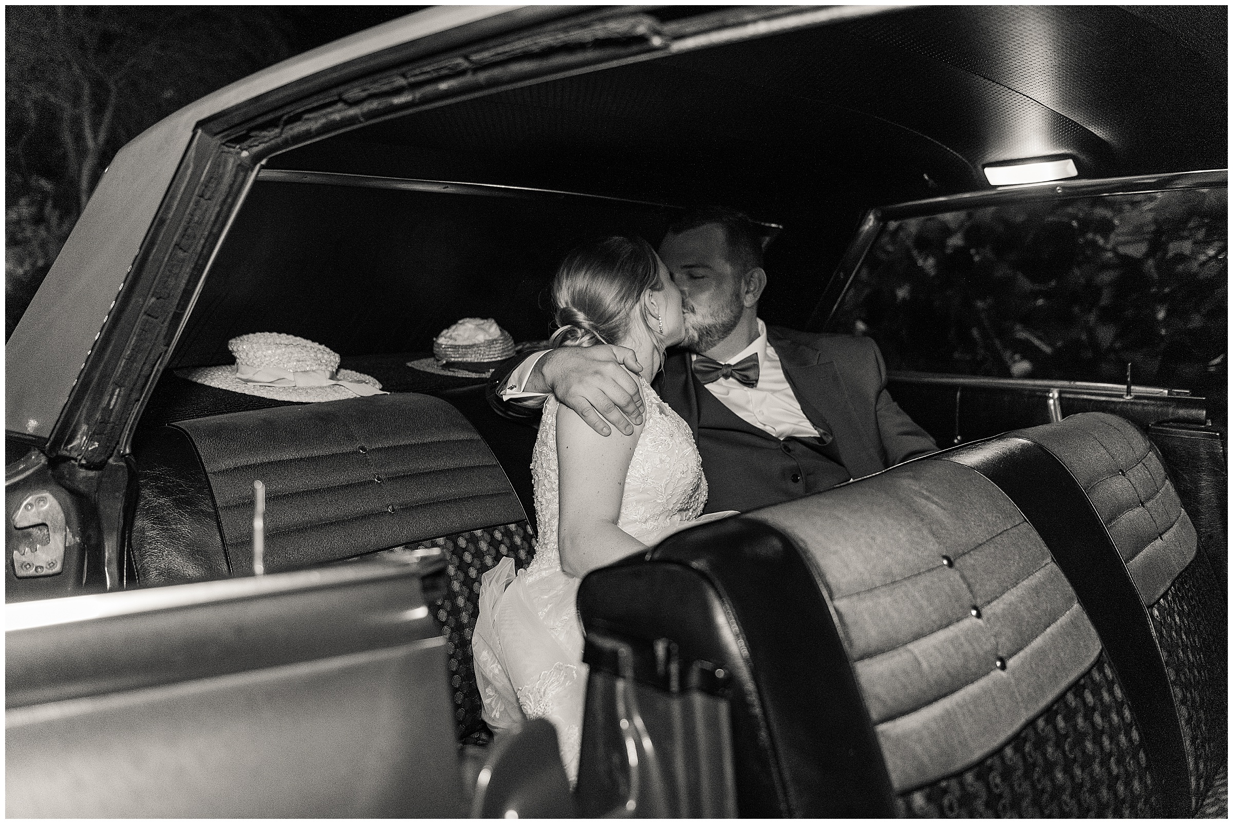 Bride and groom kissing in the back of their getaway car 