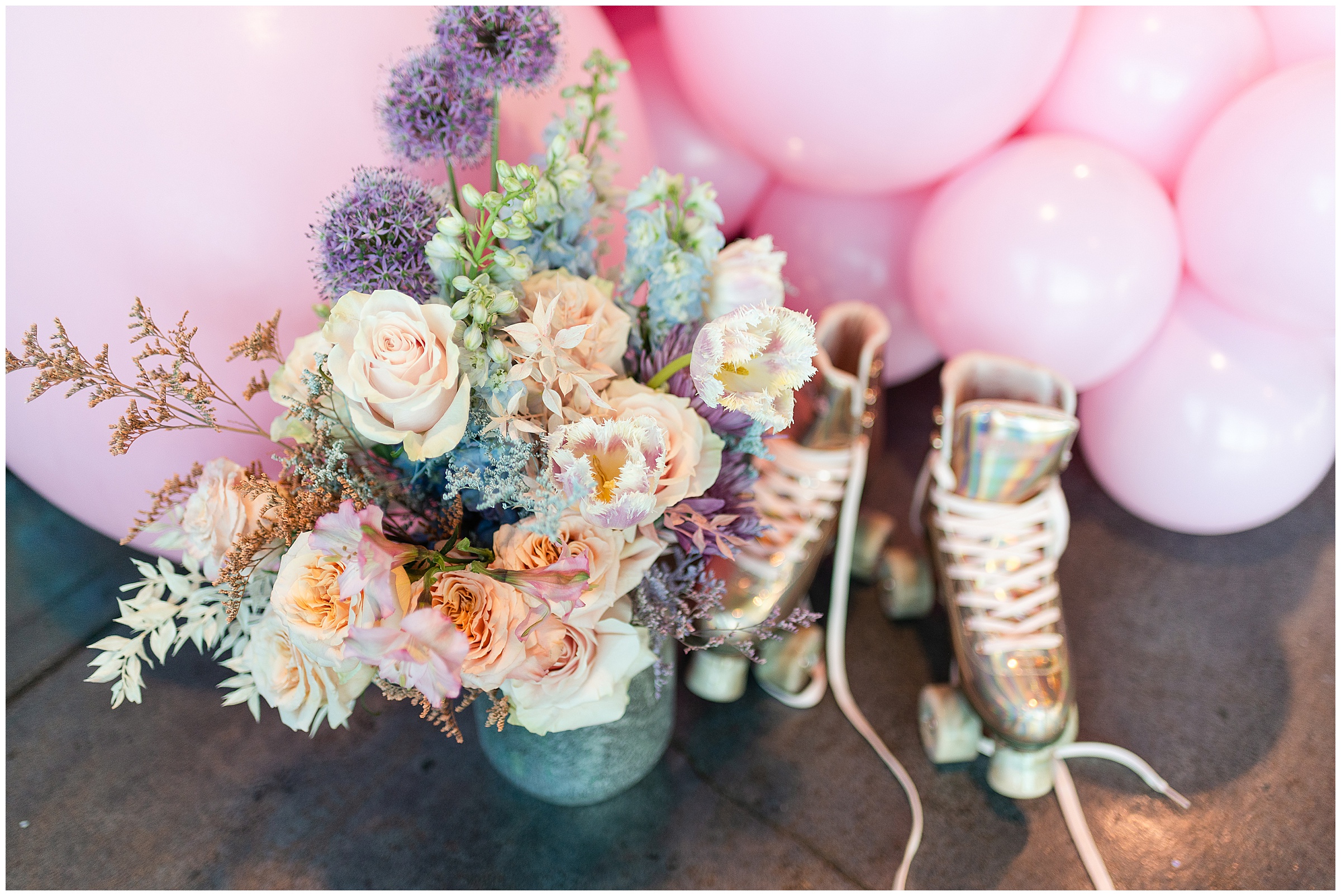 Pastel colored balloon arch with florals and rose gold roller skates