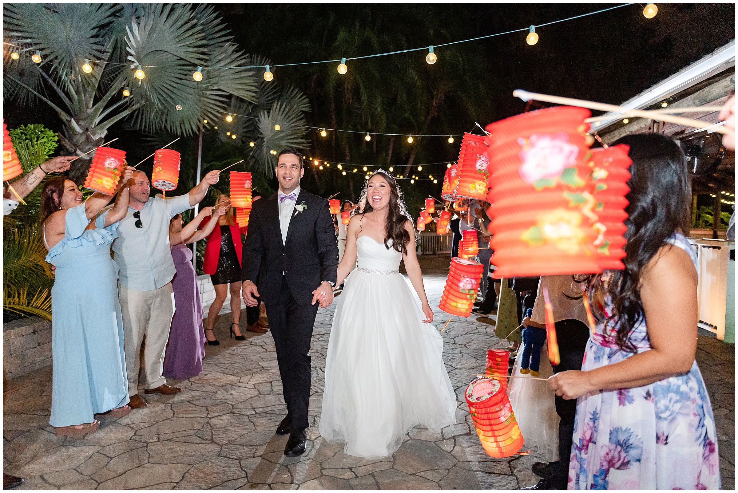 Bride and groom walking through an exit of lanterns at their Paradise Cove Wedding in Orlando, FL