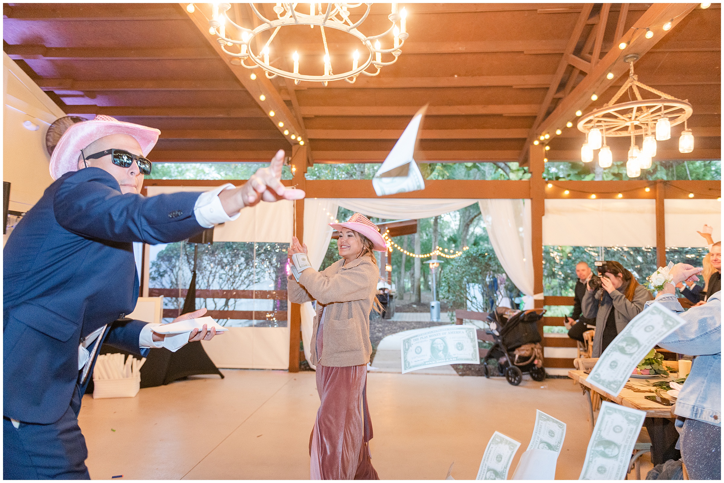 Fun bridal party reception entrance with bridemaid and groomsmen with cowboy hats and throwing fake money around