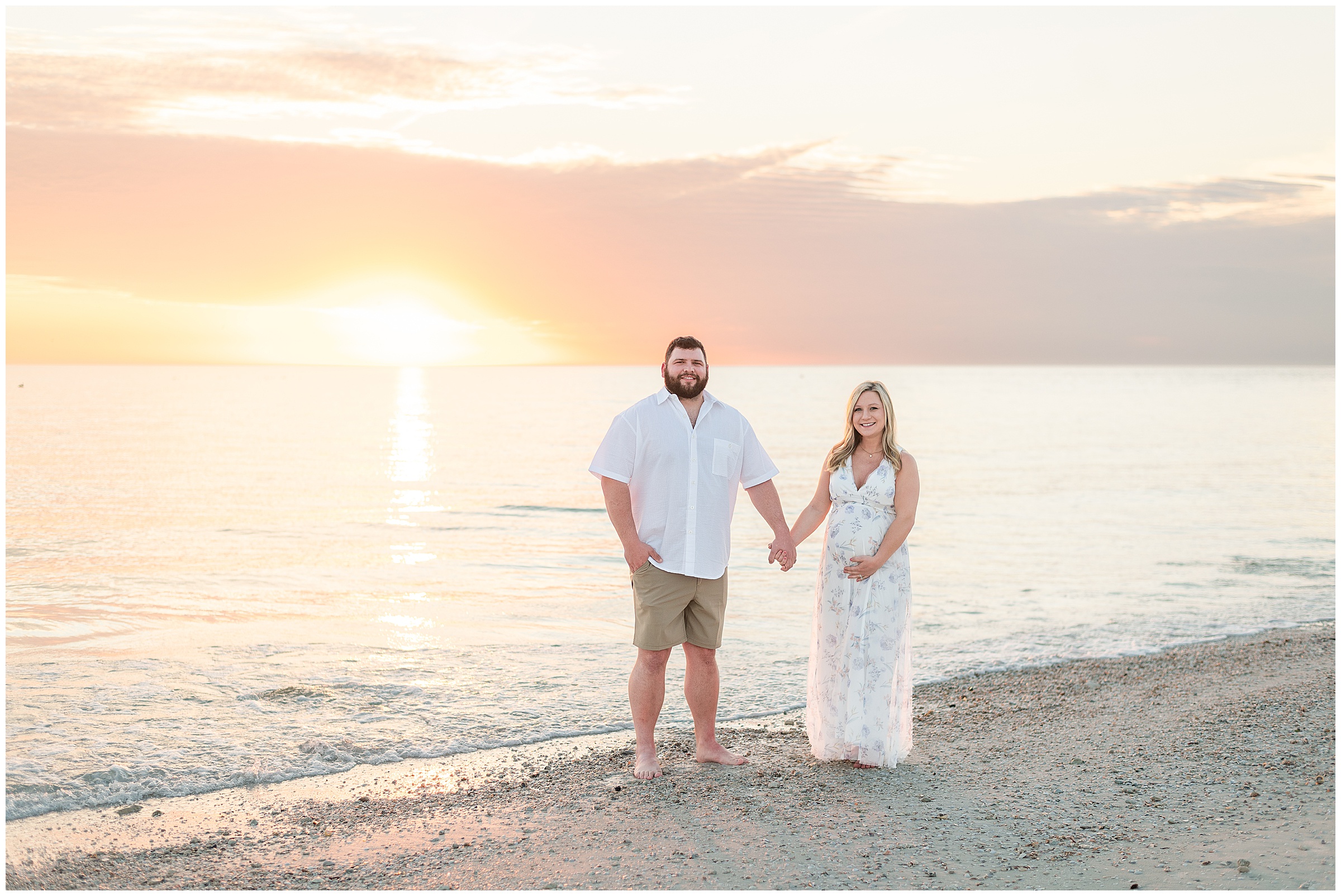 A couple posing for Maternity photos while the sun sets behind them on the beach at Honeymoon Island State Park in Florida. 